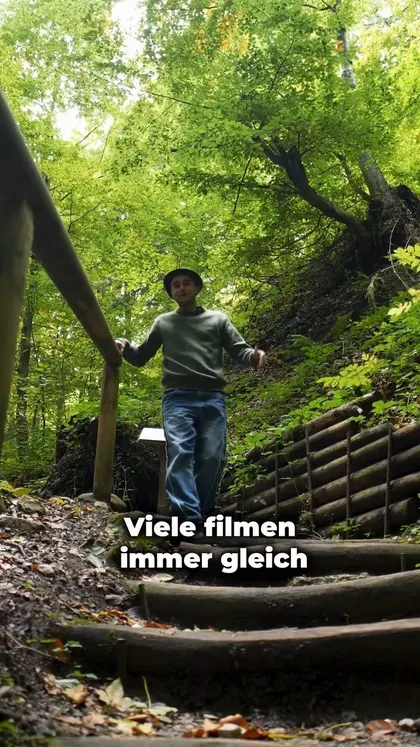Behind the Scenes: Jasin geht mit der Kamera eine Waldtreppe hinunter